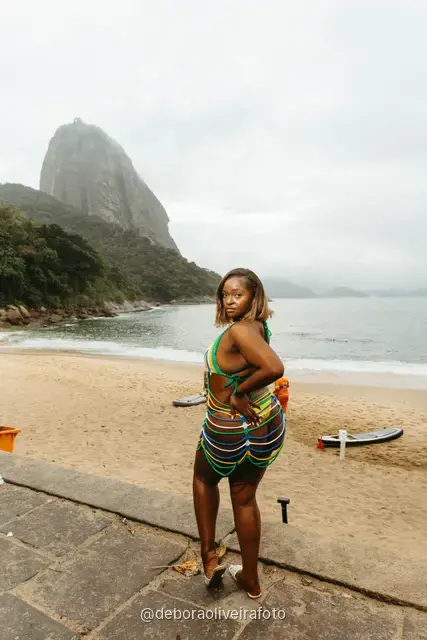 Woman in yellow and green at Praia Vermelha with Sugarloaf Mountain behind, Rio de Janeiro