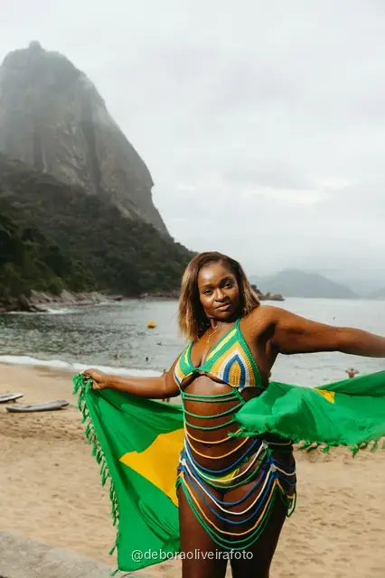 Mujer de amarillo y verde en Praia Vermelha con el Pan de Azúcar detrás, en Río de Janeiro