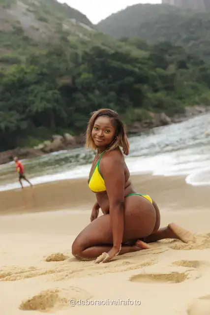 Woman in yellow and green at Praia Vermelha with Sugarloaf Mountain behind, Rio de Janeiro