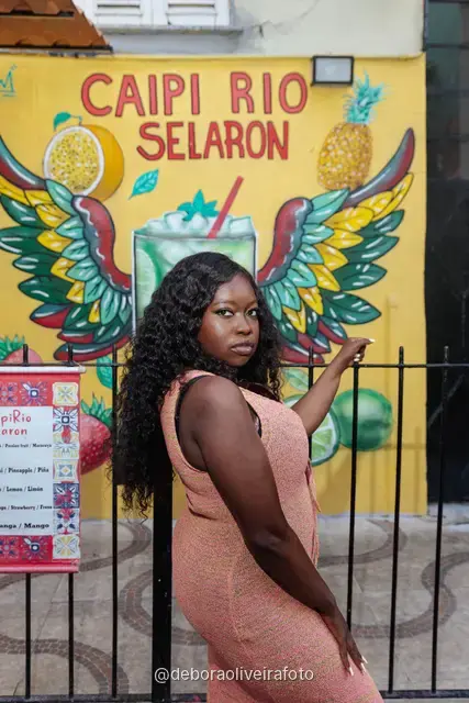 Mujer con vestido de crochet durazno frente a la pared de azulejos rojos y el mural amarillo de la Escalinata Selarón