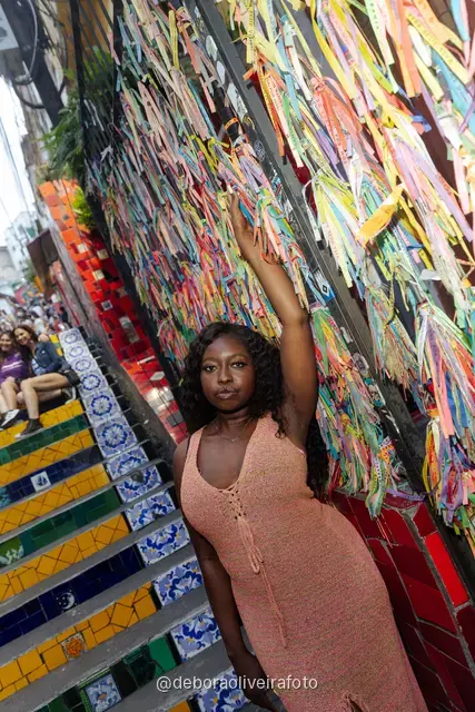 Mujer con vestido de crochet durazno frente a la pared de cintas de colores cerca de la Escalinata Selarón