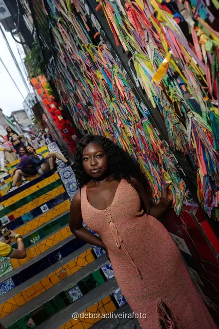 Mujer con vestido de crochet durazno frente a la pared de cintas de colores cerca de la Escalinata Selarón