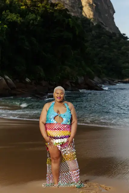 Woman in a sequin mermaid look walking in the water at Praia Vermelha with Sugarloaf Mountain behind